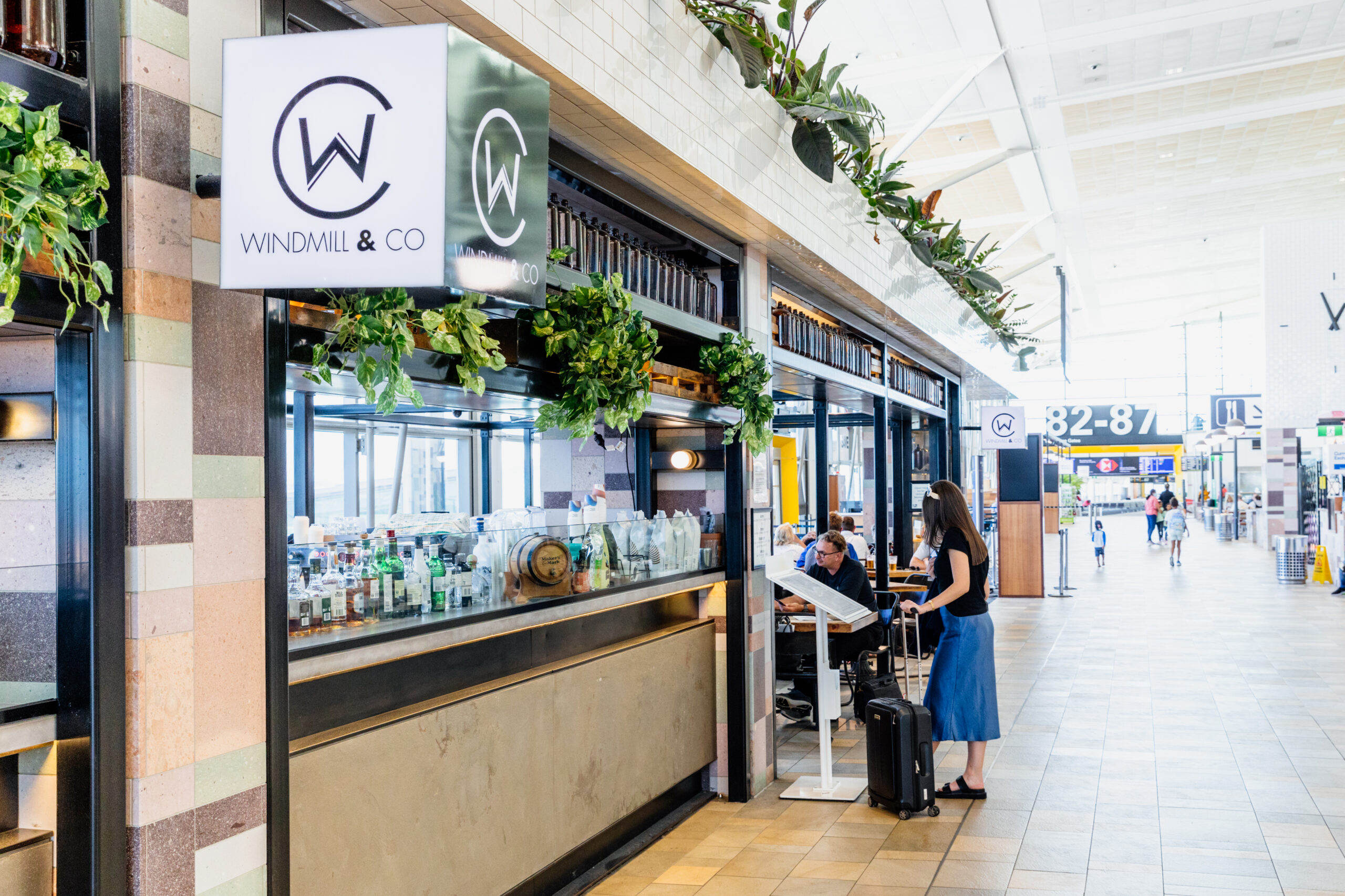 A young lady with a suitcase looking at a menu in an airport terminal