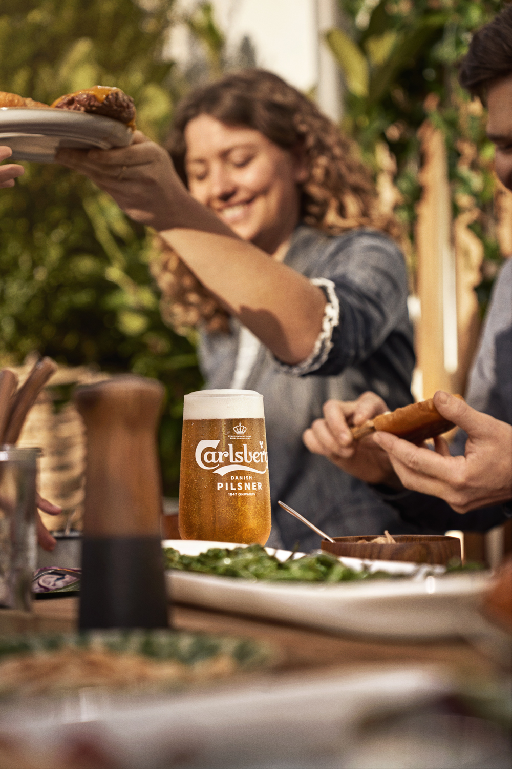 Focus on Carlsberg beer with woman in background at table