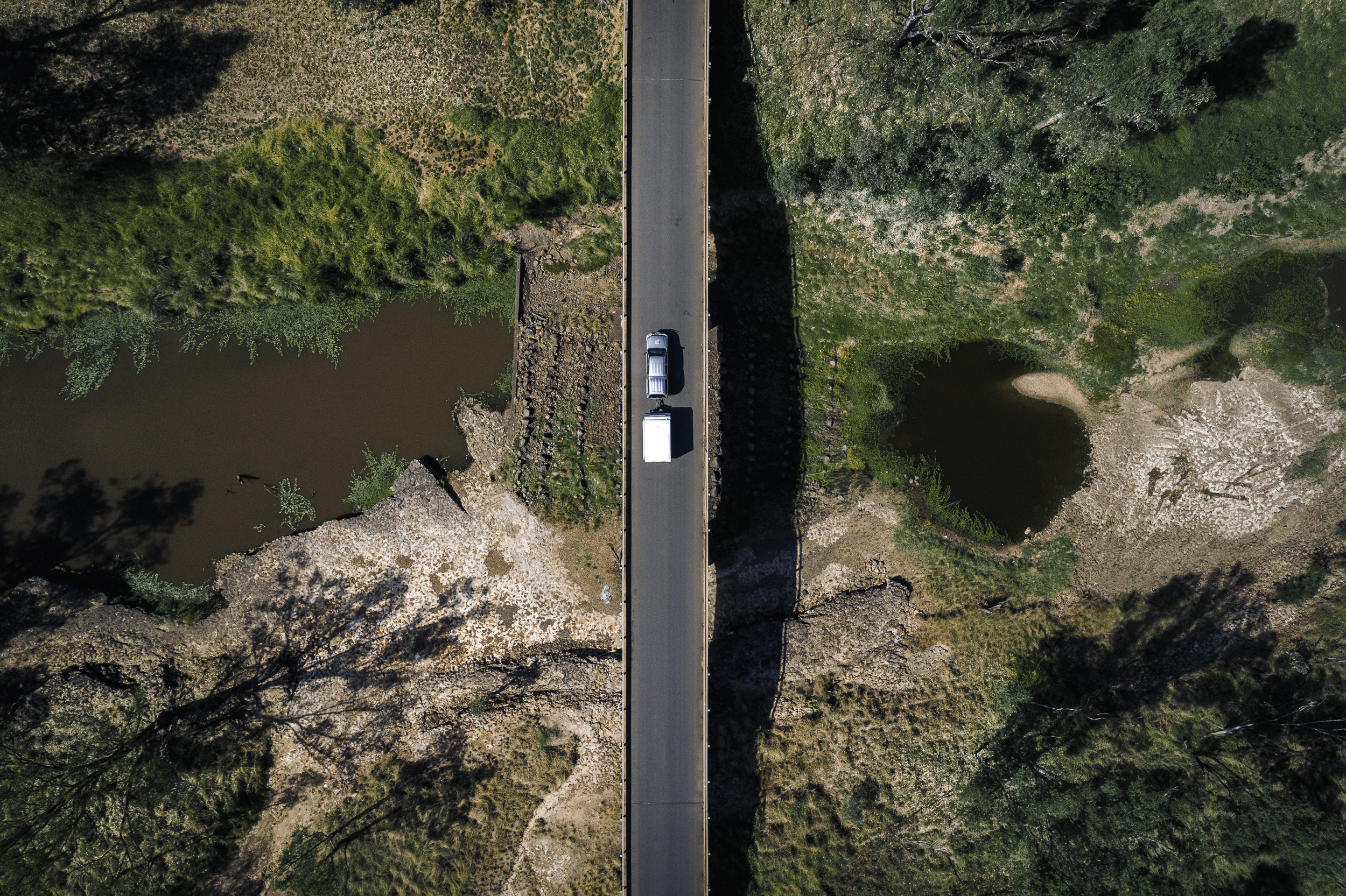 Car with camper trailer driving over bridge