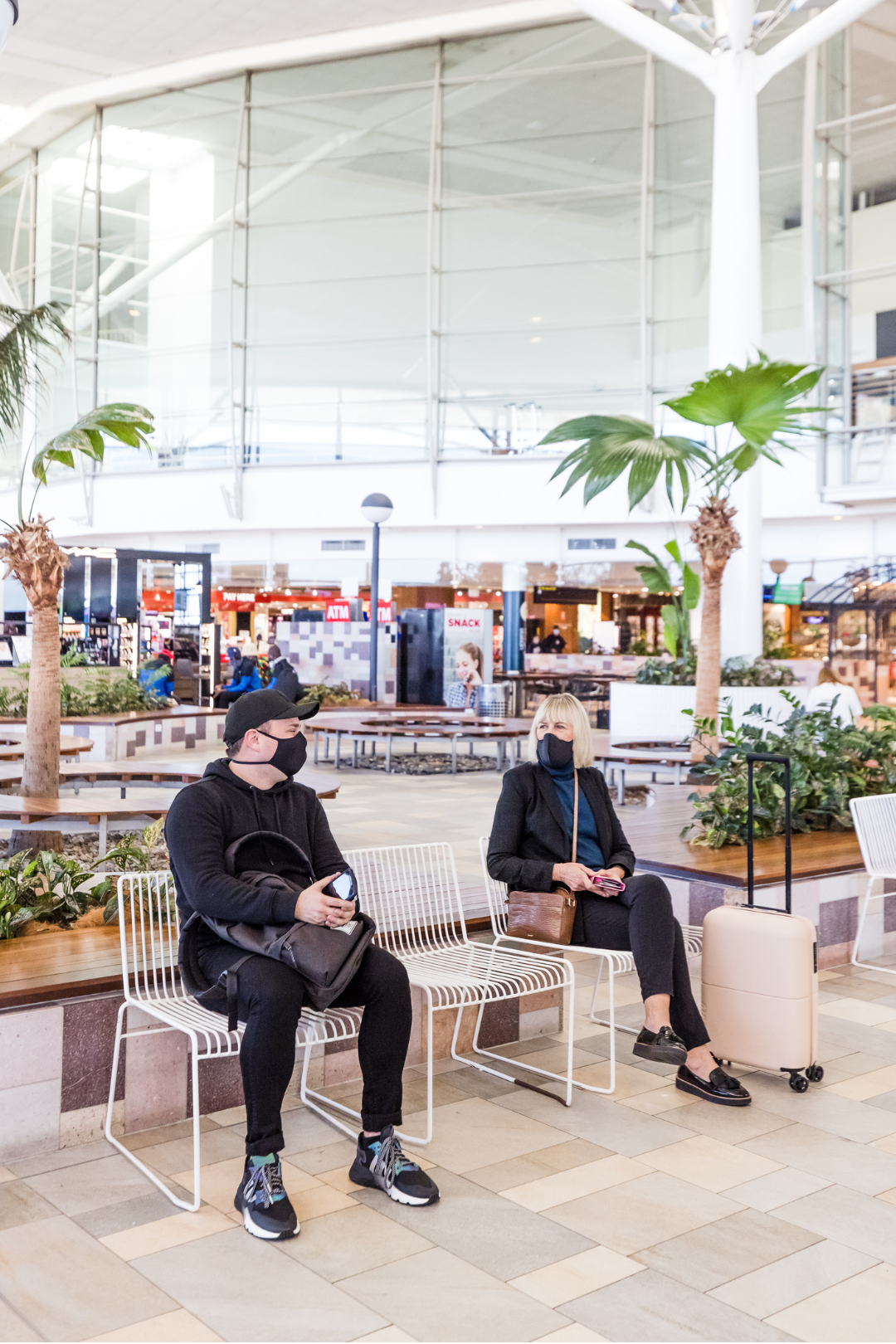 Two people wearing masks chatting at airport