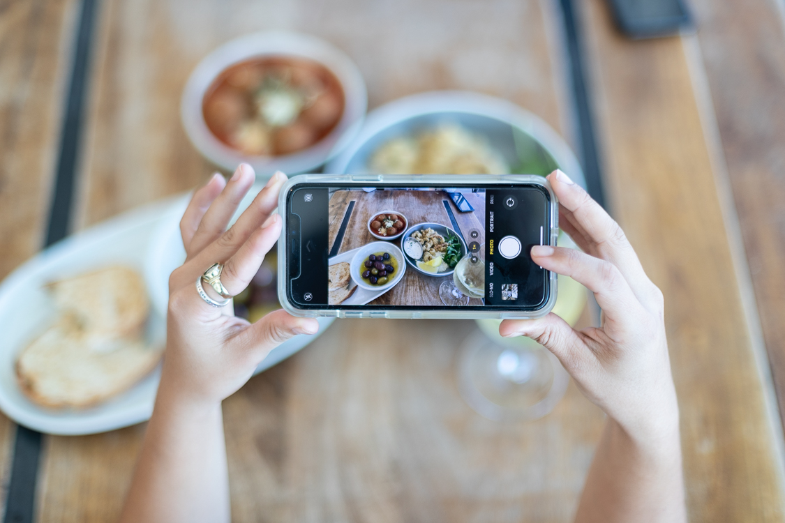 Person taking photos on phone of food