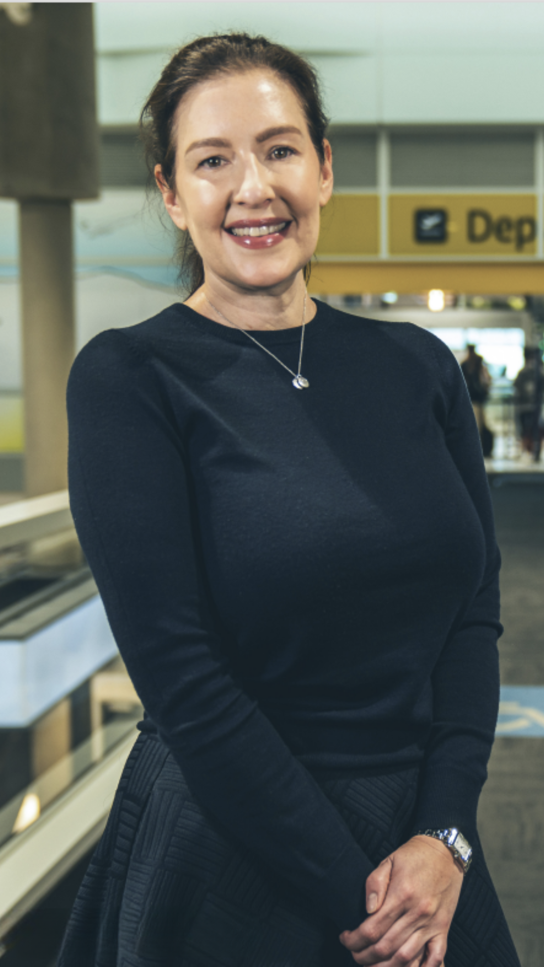 Woman standing at airport smiling